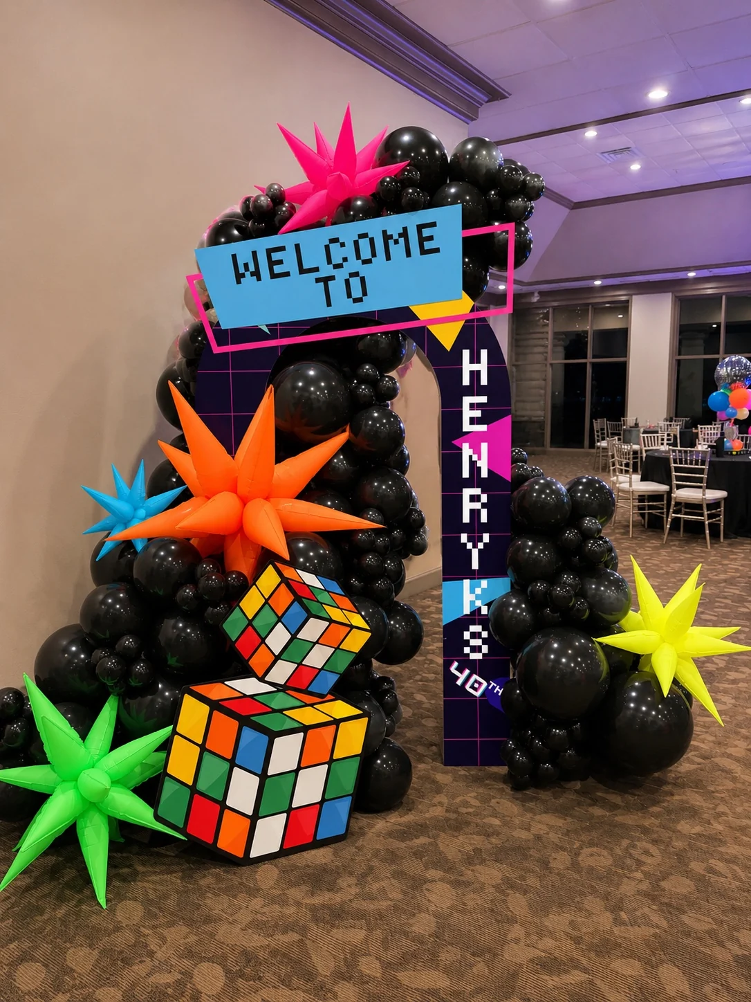 Completed 1980s party entrance with custom graphics and balloon installation
