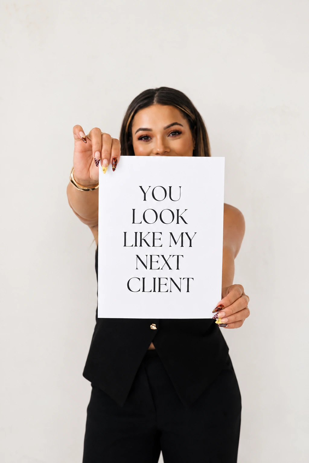 Jenica holding a sign that reads You look like my next client